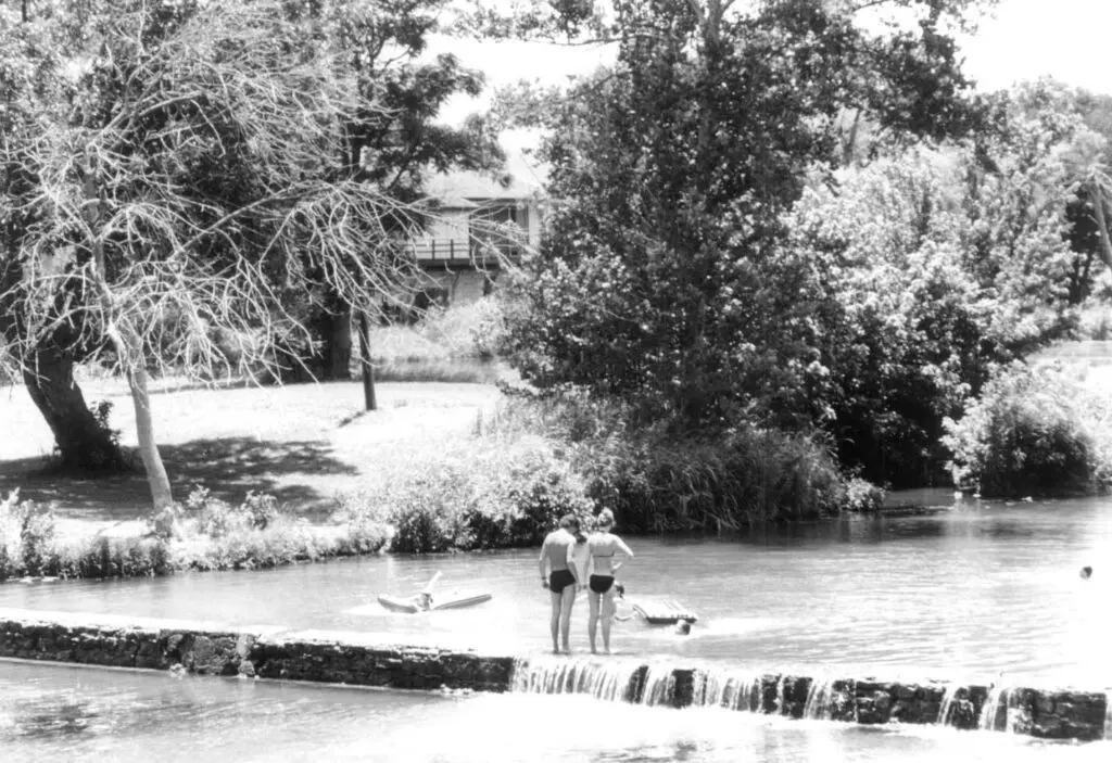 People enjoying a day by the stream in Sirena Park, Salado, Texas, in a historic photo.