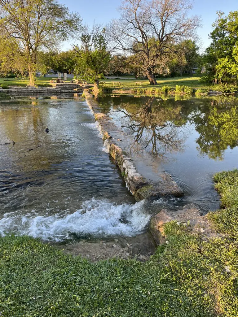 Water flowing over a small dam in Salado Creek at Sirena Park in Salado, Texas.